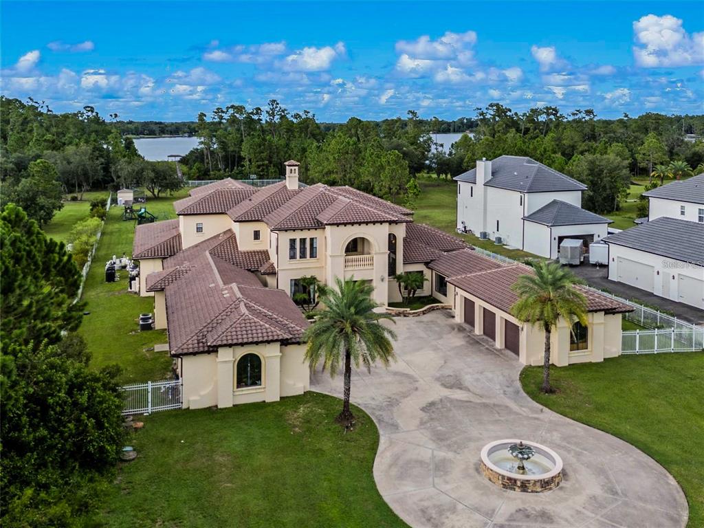 An aerial view of a large Mediterranean-style house with a tile roof and circular fountain — 5251 CARSON STREET, ST CLOUD, FL