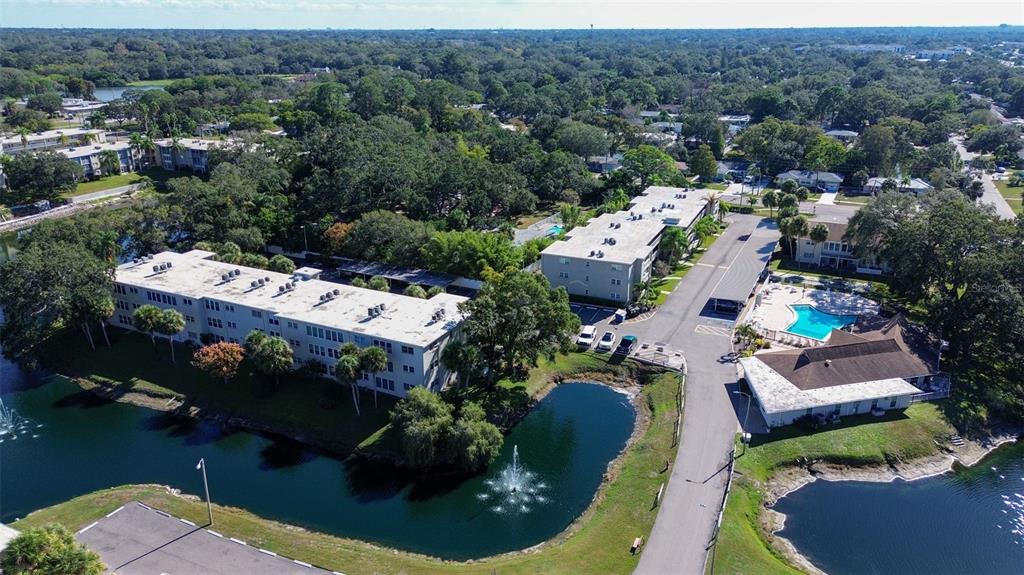 An aerial view of an apartment complex with two buildings, a pool, and a pond — 940 VIRGINIA STREET UNIT 304, DUNEDIN, FL