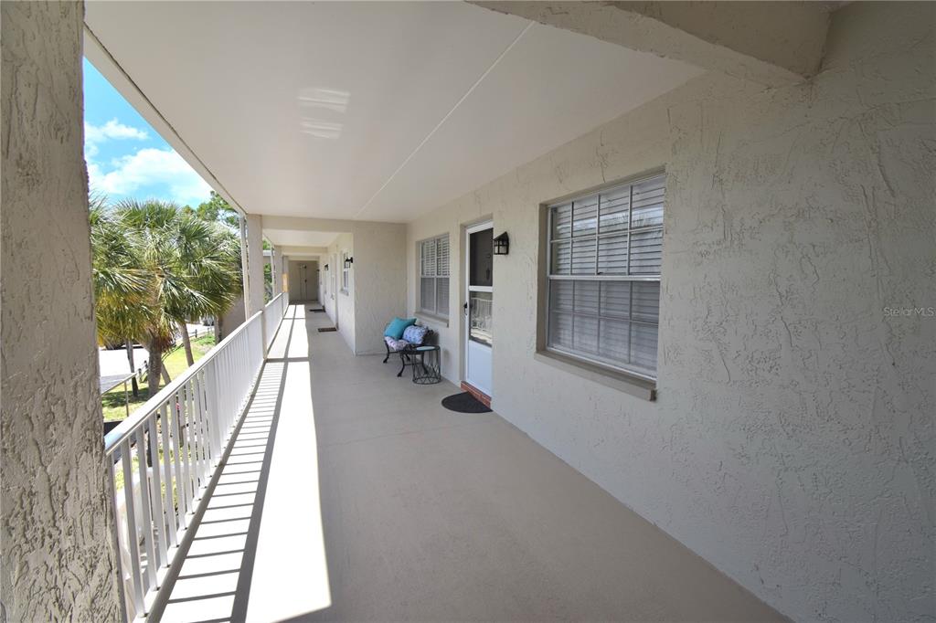 An exterior view of a covered apartment balcony with a white railing and stucco walls — 940 VIRGINIA STREET UNIT 304, DUNEDIN, FL