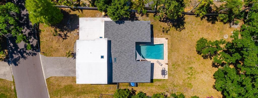 An aerial view shows a house with a gray roof, a pool, and a paved driveway — 1424 S EVERGREEN AVENUE, CLEARWATER, FL