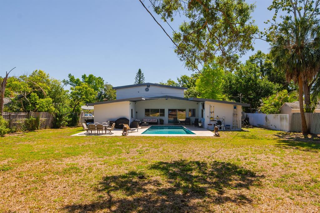 A backyard view of a house with a swimming pool, patio, and large lawn — 1424 S EVERGREEN AVENUE, CLEARWATER, FL