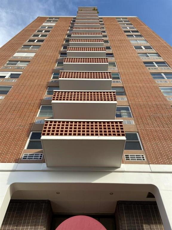 A low-angle view of a tall brick apartment building featuring stacked balconies and windows — 4015 BAYSHORE UNIT 17A, TAMPA, FL