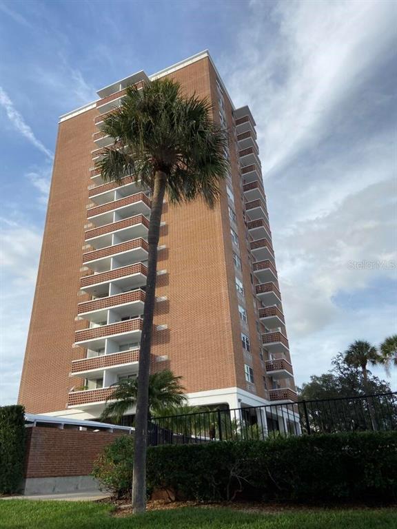 A tall, brick high-rise apartment building stands behind a palm tree and a black fence — 4015 BAYSHORE UNIT 17A, TAMPA, FL