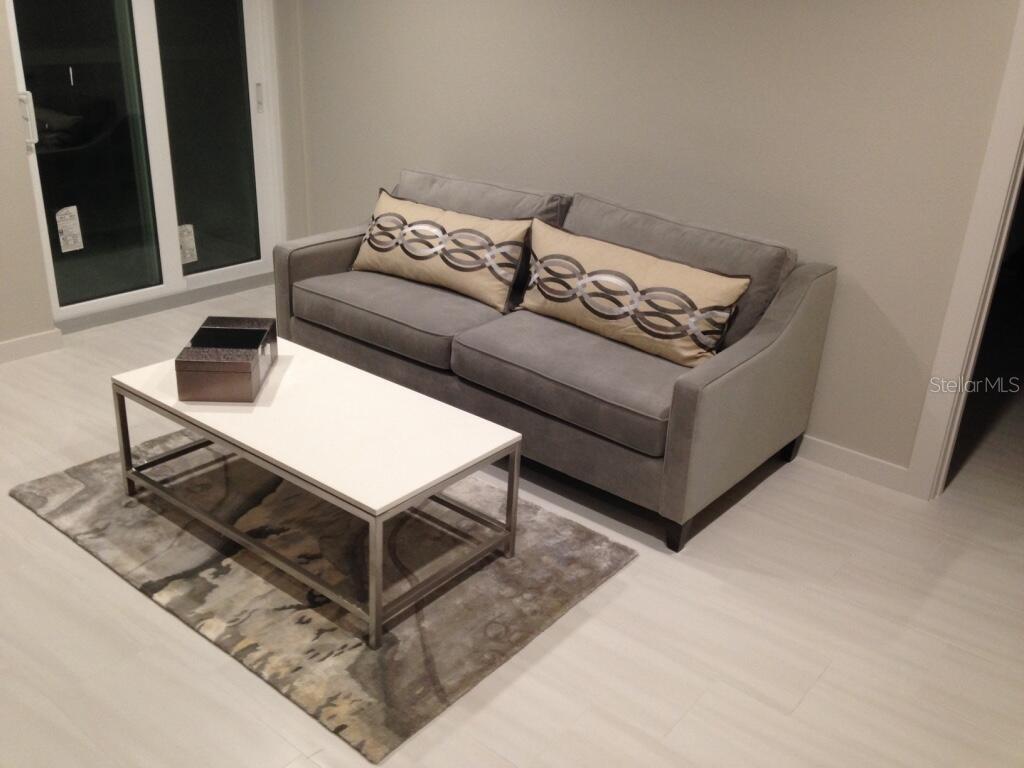 A gray sofa with patterned pillows sits on a rug before a white coffee table — 4015 BAYSHORE UNIT 17A, TAMPA, FL
