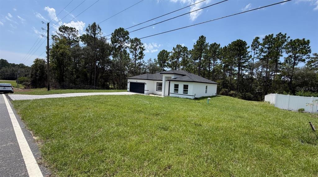 A white single-story house with a dark roof and garage sits on a grassy lot — 794 MARION OAKS MANOR, OCALA, FL