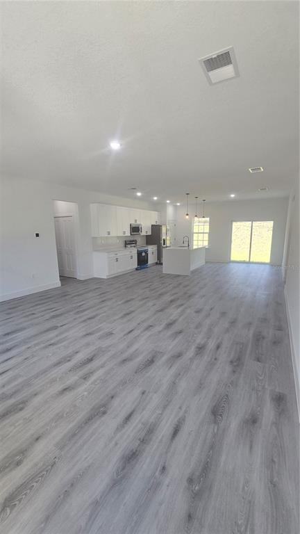 An open-concept kitchen and living area featuring white cabinetry, a kitchen island, and gray flooring — 794 MARION OAKS MANOR, OCALA, FL