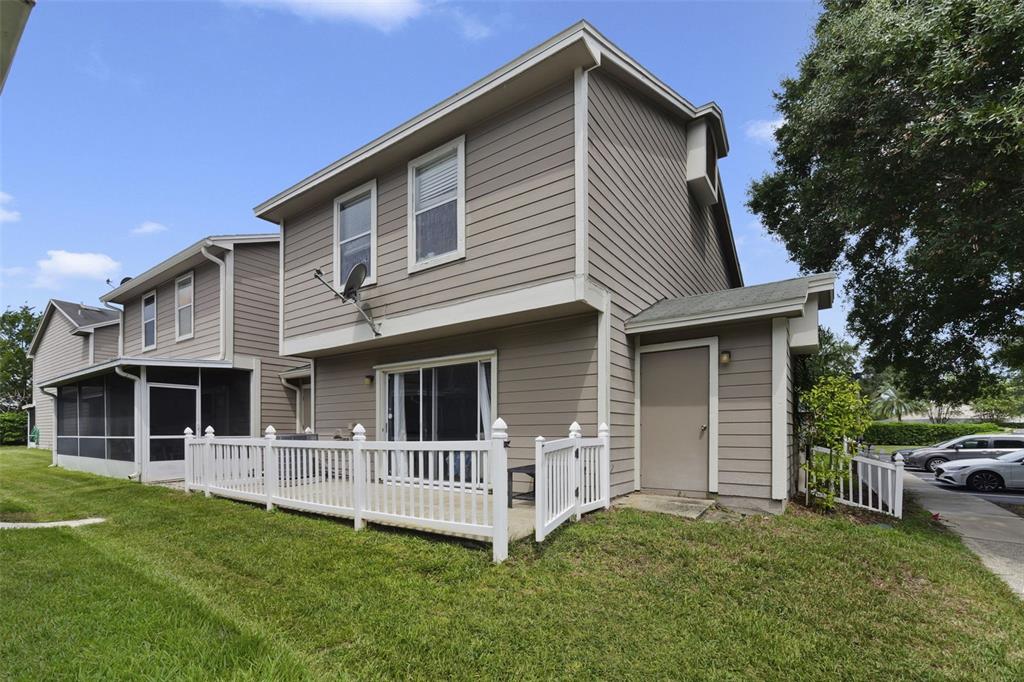 A two-story townhouse exterior features a white vinyl fence, a patio, and a storage closet — 942 SYKES COURT UNIT 101, ORLANDO, FL
