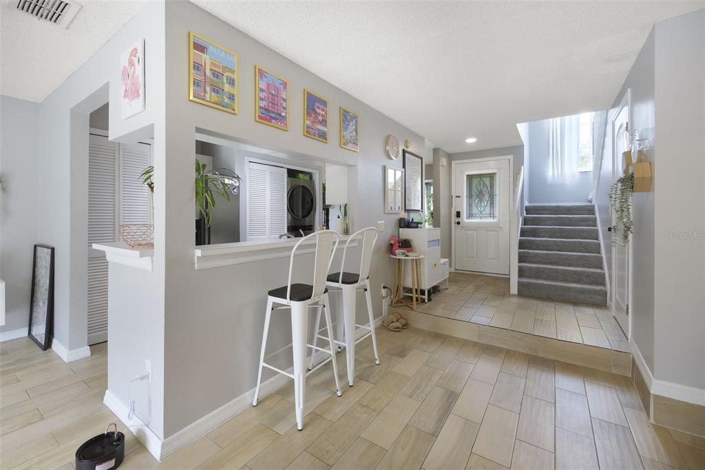 A living area features a breakfast bar with two stools, light flooring, and a staircase — 942 SYKES COURT UNIT 101, ORLANDO, FL