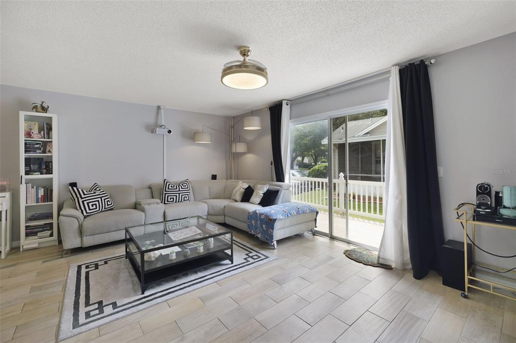 A living room features a sectional sofa, glass coffee table, and sliding doors to a patio — 942 SYKES COURT UNIT 101, ORLANDO, FL