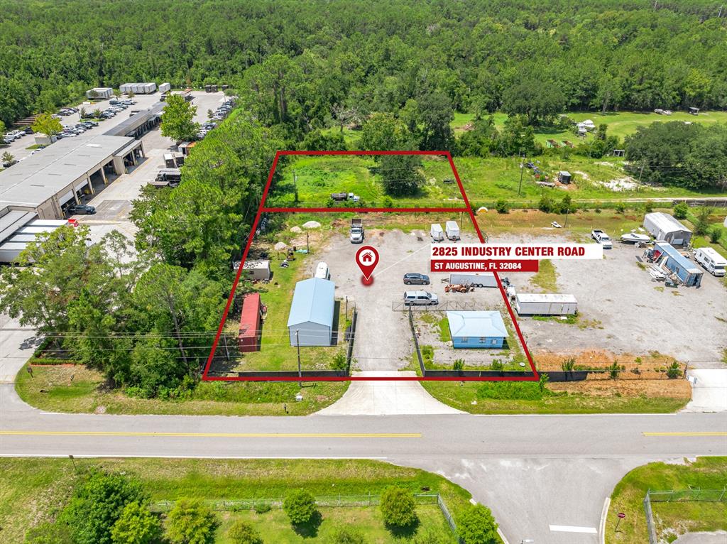 An aerial view shows a fenced industrial lot with two small buildings and gravel parking — 2825 INDUSTRY CENTER ROAD, ST AUGUSTINE, FL