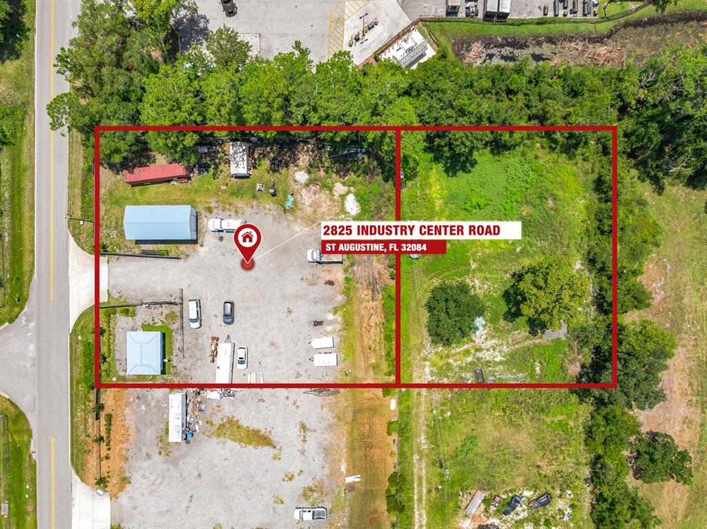 An aerial view shows a gravel lot with several small structures and an adjacent undeveloped area — 2825 INDUSTRY CENTER ROAD, ST AUGUSTINE, FL