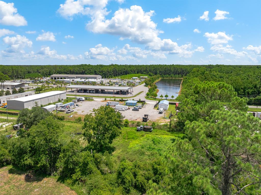 An aerial view shows a commercial property with a parking lot, buildings, and a pond — 2825 INDUSTRY CENTER ROAD, ST AUGUSTINE, FL