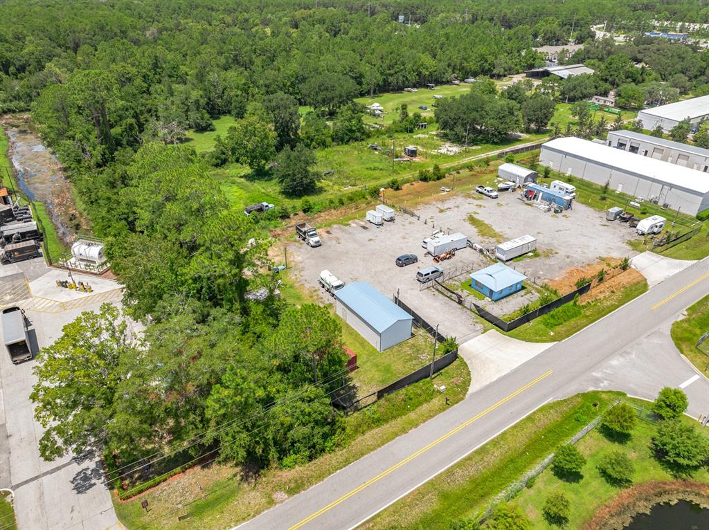 An aerial view shows a fenced commercial lot with storage buildings, trailers, and parked vehicles — 2825 INDUSTRY CENTER ROAD, ST AUGUSTINE, FL