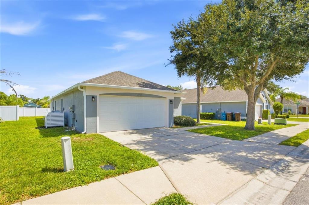 A single-story house with a two-car garage, a concrete driveway, and a large shade tree — 2712 KOKOMO LOOP, HAINES CITY, FL