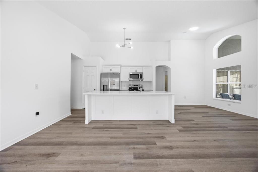 A modern kitchen with white cabinetry, a central island, and wood-look flooring — 2712 KOKOMO LOOP, HAINES CITY, FL