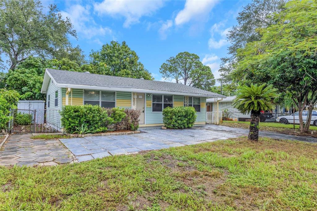 A single-story house with light green siding, a paved front patio, and surrounding trees — 5621 11TH AVENUE N, ST PETERSBURG, FL
