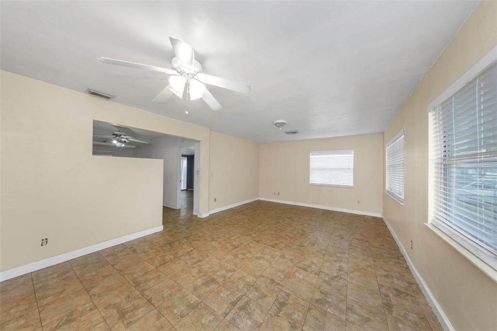 An empty room with beige walls, tile flooring, a ceiling fan, and two windows — 5621 11TH AVENUE N, ST PETERSBURG, FL