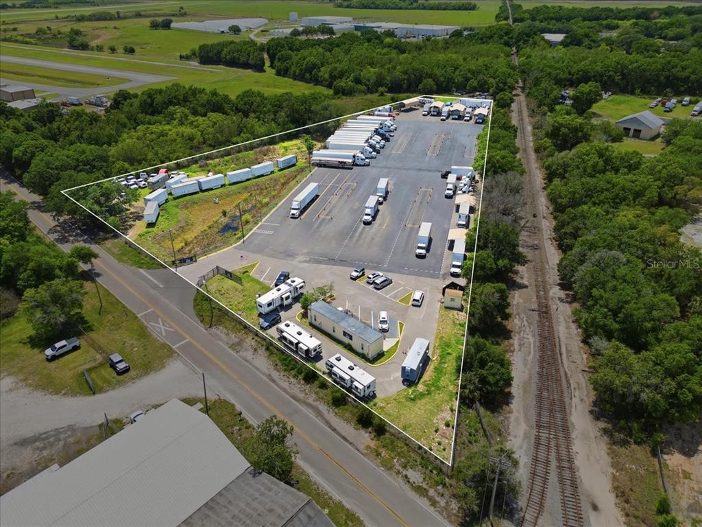 An aerial view shows a triangular commercial lot with a parking area, trailers, and buildings — 100 S AIRPORT ROAD, LAKE WALES, FL