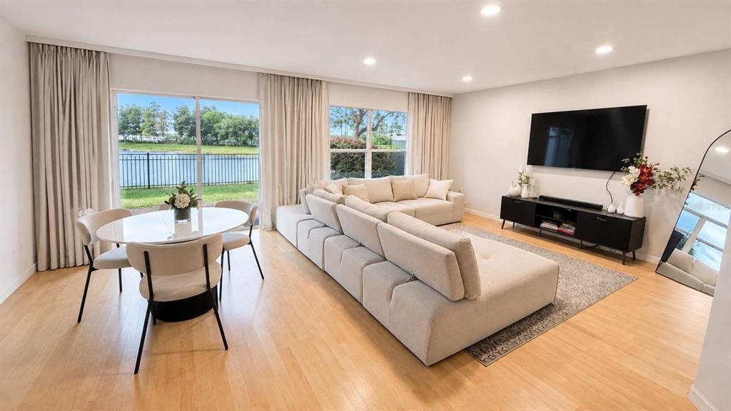 A living and dining area features light wood floors, a sectional sofa, and lake views — 2548 HASSONITE STREET, KISSIMMEE, FL
