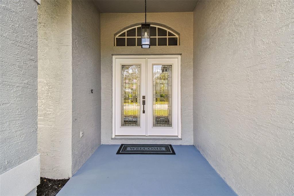 The exterior of a house features a gray stucco facade, a covered entryway, and white trim — 8818 POE DRIVE, HUDSON, FL