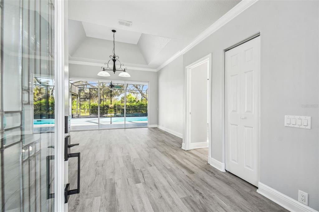 An entryway leads into a living room with gray wood floors, a tray ceiling, and pool — 8818 POE DRIVE, HUDSON, FL