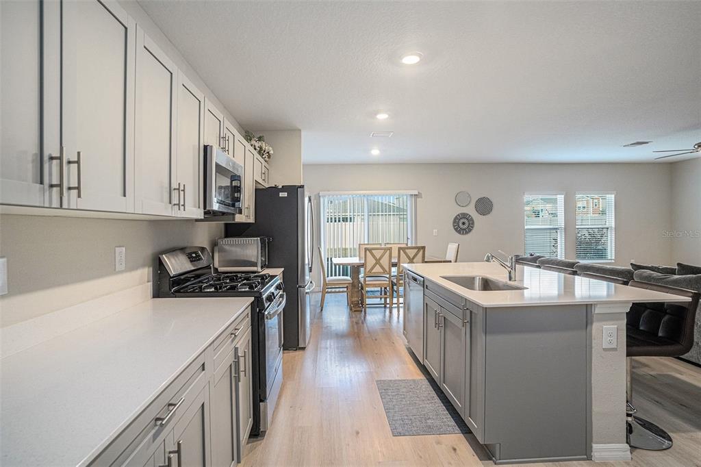 A kitchen features gray cabinets, white countertops, a center island, and stainless steel appliances — 12940 HAWKSTONE TRAIL BOULEVARD, LITHIA, FL