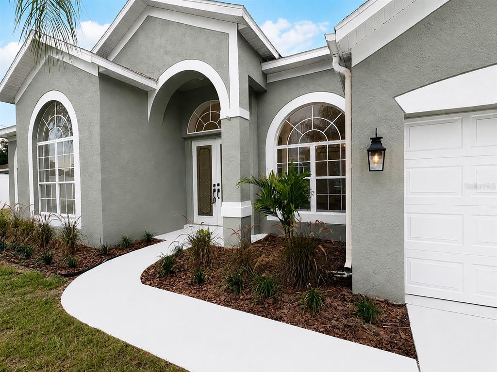 The exterior of a gray house features a white walkway, arched windows, and a garage — 2532 BELLWOOD DRIVE, BRANDON, FL