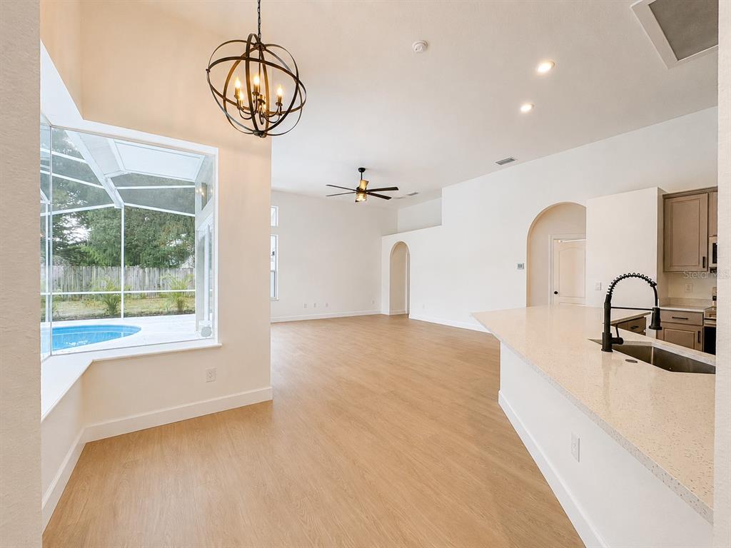 A bright kitchen and dining area features light wood flooring, a pool view, and pendant lighting — 2532 BELLWOOD DRIVE, BRANDON, FL