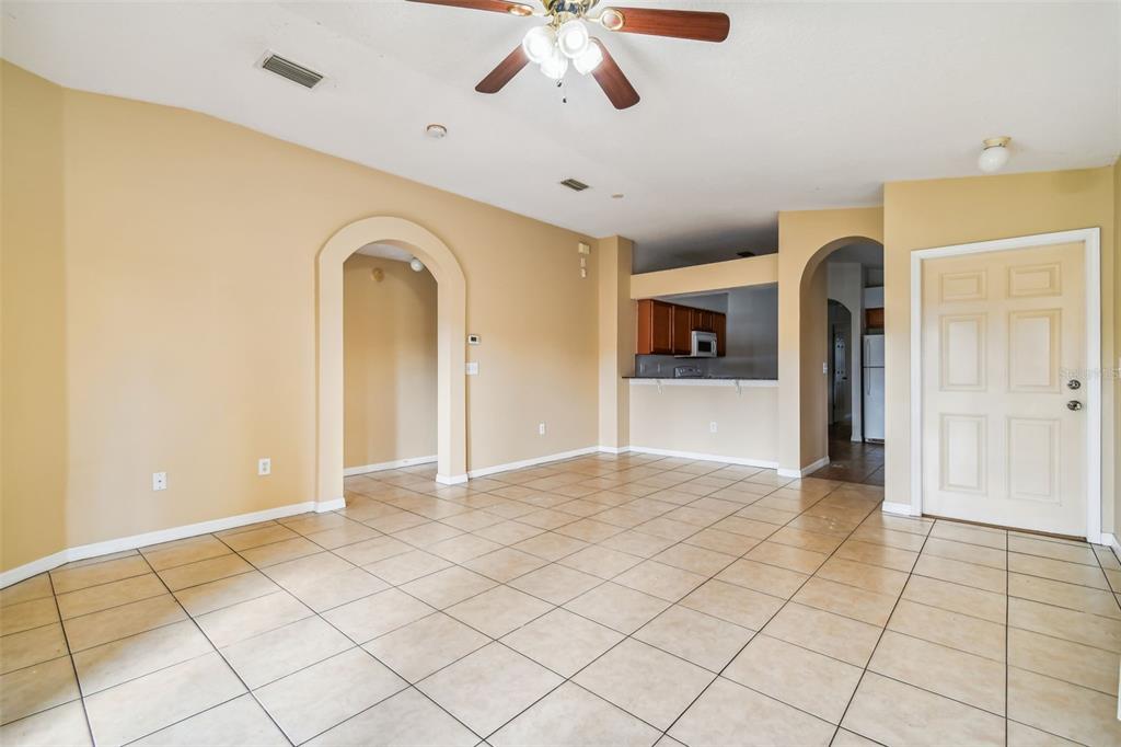 An open living area features beige walls, tiled floors, an arched doorway, and a ceiling fan — 7956 CARRIAGE POINTE DRIVE, GIBSONTON, FL