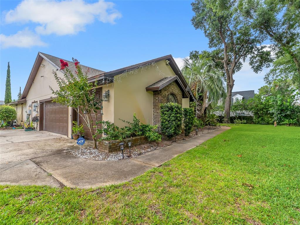 A side view of a house exterior featuring a garage, brick accents, and a lawn — 1407 HEMPEL AVENUE, WINDERMERE, FL