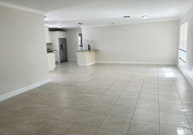 An open-concept living area with light-colored tile flooring and a view into the kitchen — 110 PINE AVENUE, OSPREY, FL