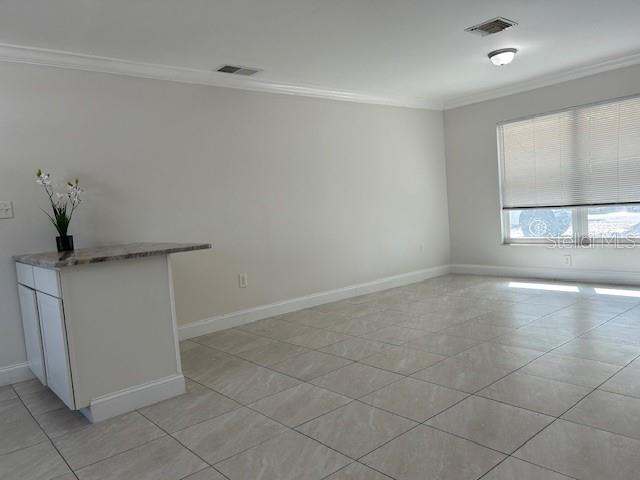 A room with light-colored tile flooring, a small kitchen island, and a window with blinds — 110 PINE AVENUE, OSPREY, FL