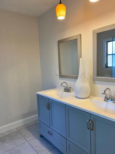 A bathroom features a double vanity with blue cabinets, white countertops, and two mirrors — 110 PINE AVENUE, OSPREY, FL
