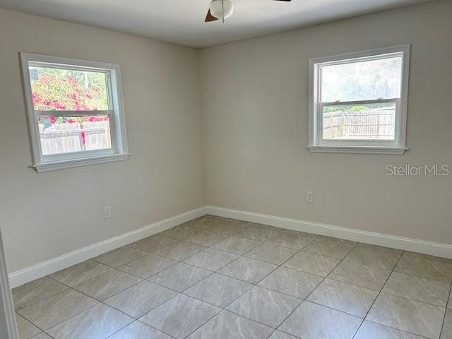 An empty bedroom features light-colored walls, large windows, and light-toned tile flooring — 110 PINE AVENUE, OSPREY, FL