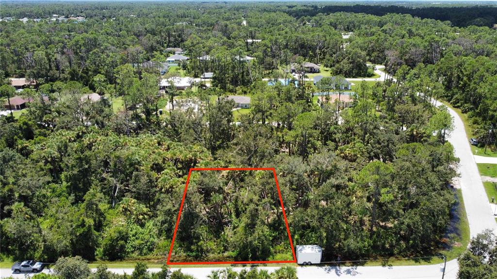 An aerial view shows a rectangular, wooded vacant lot outlined in red along a paved road — SHAWNEE TER, NORTH PORT, FL