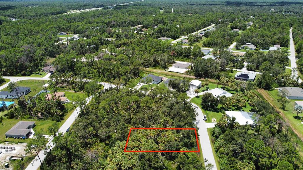An aerial view shows a rectangular, wooded vacant lot outlined in red within a residential neighborhood — SHAWNEE TER, NORTH PORT, FL