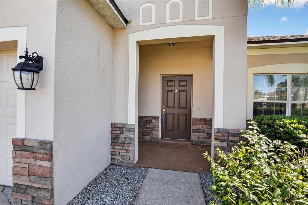 The exterior entrance features a brown door, stone veneer accents, and a concrete walkway — 9023 41ST STREET E, PARRISH, FL