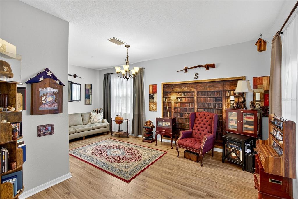 A living room features a red armchair, a sofa, a rug, and a library-themed wall mural — 9023 41ST STREET E, PARRISH, FL
