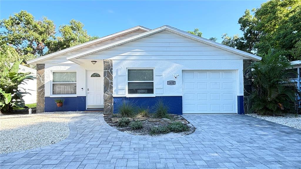 The exterior of a house features white siding, blue lower walls, and stone accents — 2431 LOMA LINDA STREET, SARASOTA, FL