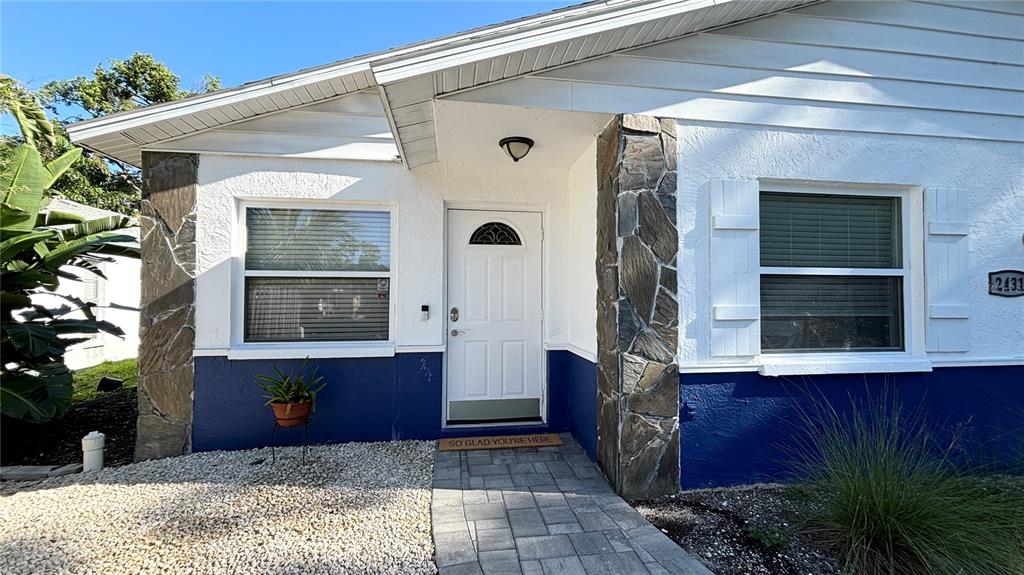 The exterior of a house features white stucco walls, blue trim, and stone accents — 2431 LOMA LINDA STREET, SARASOTA, FL