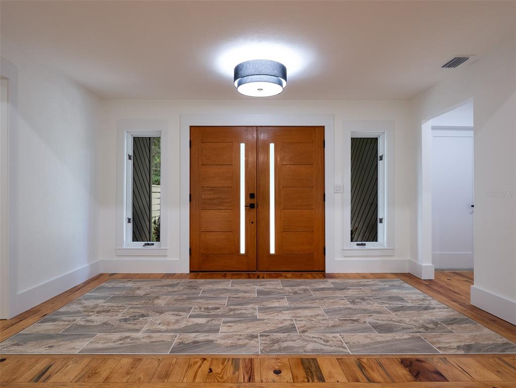 A modern home exterior features a dark wood facade, double front doors, and stone patio — 3104 NW 21ST AVENUE, GAINESVILLE, FL