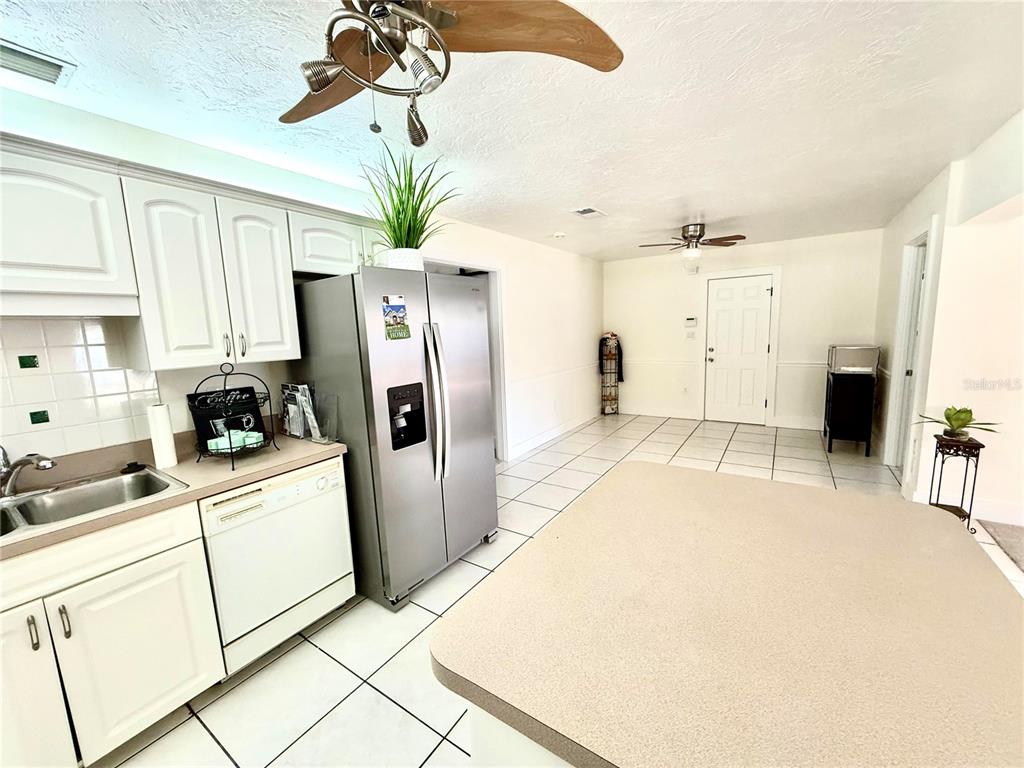 A kitchen features white cabinets, stainless steel appliances, a large island, and tiled flooring — 3715 SHARONDALE DRIVE, SARASOTA, FL