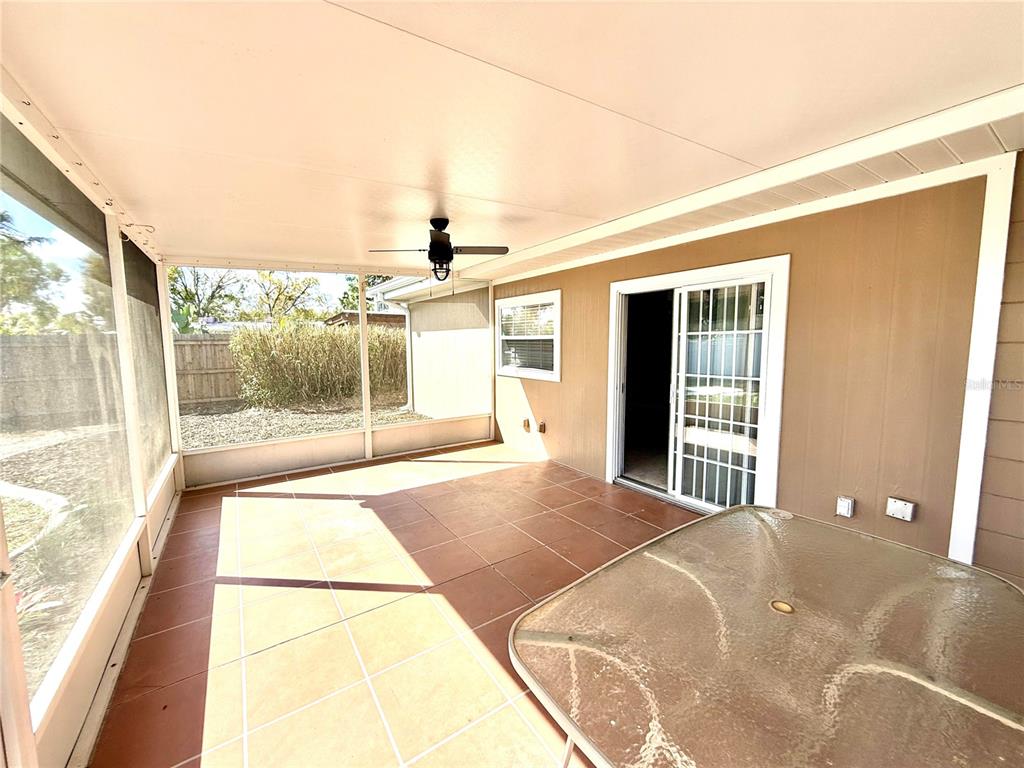 A screened-in patio features tiled flooring, a ceiling fan, and a sliding glass door — 3715 SHARONDALE DRIVE, SARASOTA, FL