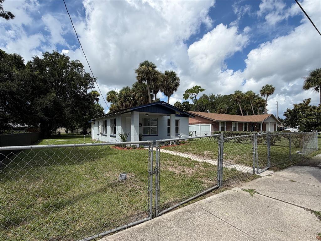 A single-story house with a white brick exterior and a chain-link fence in the yard — 234 N ADAMS STREET, DAYTONA BEACH, FL