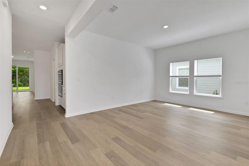 An empty room with light wood flooring, white walls, and two windows — 3217 WILLOWLEAF LANE, GREEN COVE SPRINGS, FL