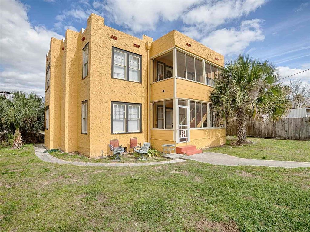 A two-story yellow stucco building features a screened-in porch and a grassy yard — 426 E CITRUS AVENUE, EUSTIS, FL