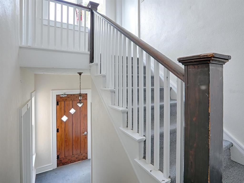 A staircase with a dark wood railing leads upward next to a wooden front door — 426 E CITRUS AVENUE, EUSTIS, FL