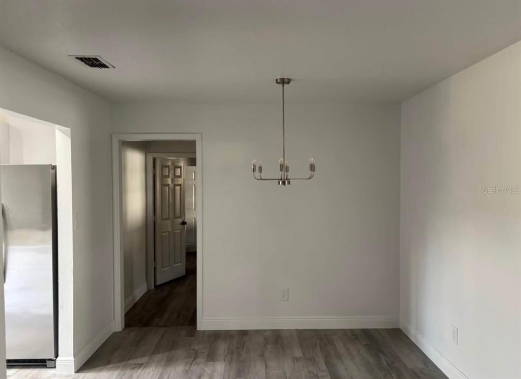 A dining area with light wood-look flooring, white walls, and a modern metal chandelier — 14915 GENTILLY PLACE, TAMPA, FL