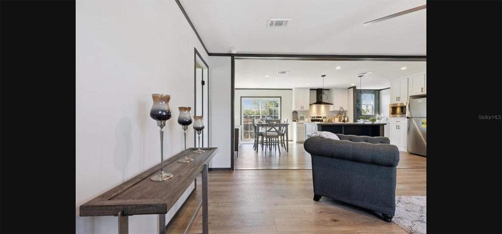 A living room features wood-look flooring, a dark wood accent wall, and gray tufted furniture — 1636 MISTLETOE STREET, BUNNELL, FL