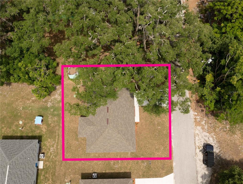 An aerial view shows a house with a shingled roof surrounded by large oak trees — 306 E GEORGIA AVENUE, BUSHNELL, FL